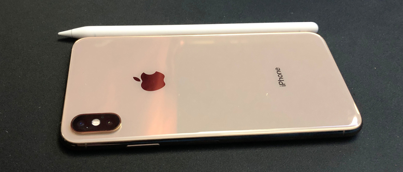 A second-generation Apple Pencil next to an iPhone XS Max