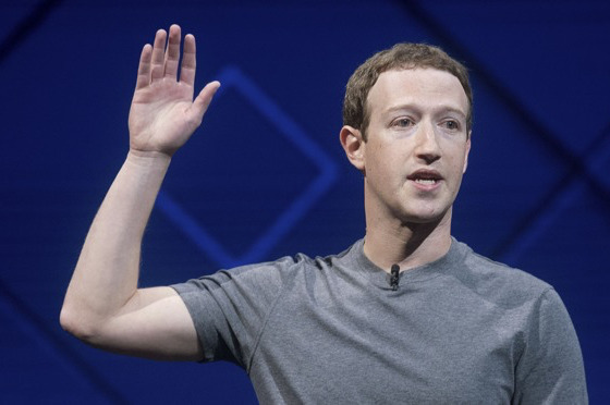 Facebook CEO Mark Zuckerberg puts his hand up for something.