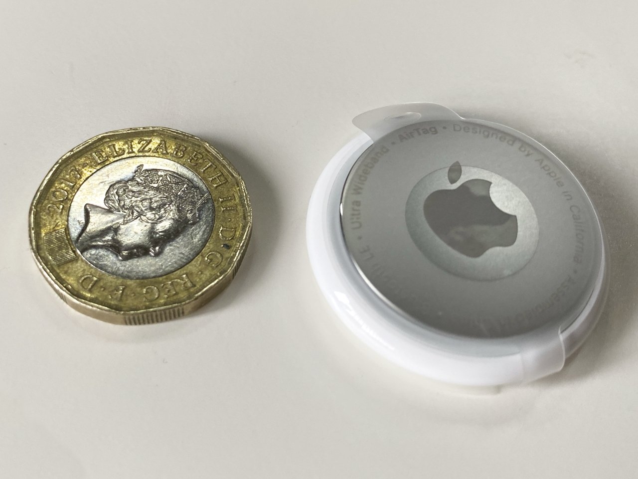 An AirTag next to a British pound coin