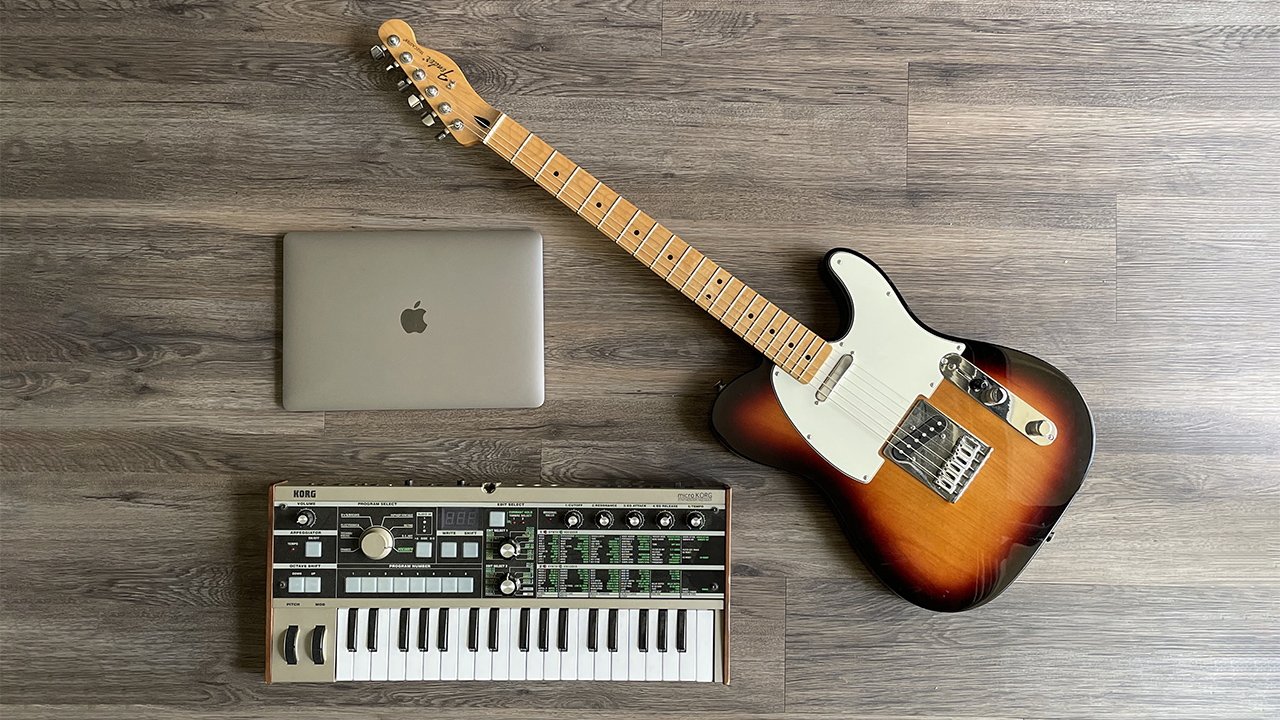 A MacBook Pro, a guitar, and a keyboard.