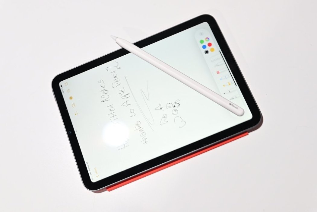 Tablet with handwritten notes and doodles, accompanied by a white stylus, on a white background.