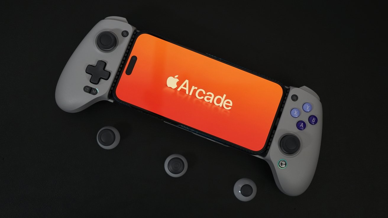 An iPhone is mounted onto a game controller with dual joysticks and multiple buttons, displaying a red-orange screen with the Apple Arcade logo, on a dark background with loose joysticks scattered around.