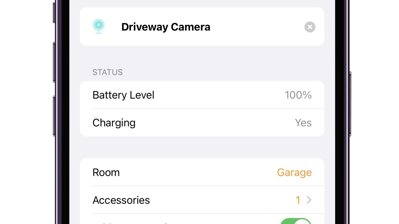 A smartphone screen displays the status of a 'Driveway Camera' with a battery level at 100% and charging, assigned to 'Garage' room with one accessory connected.