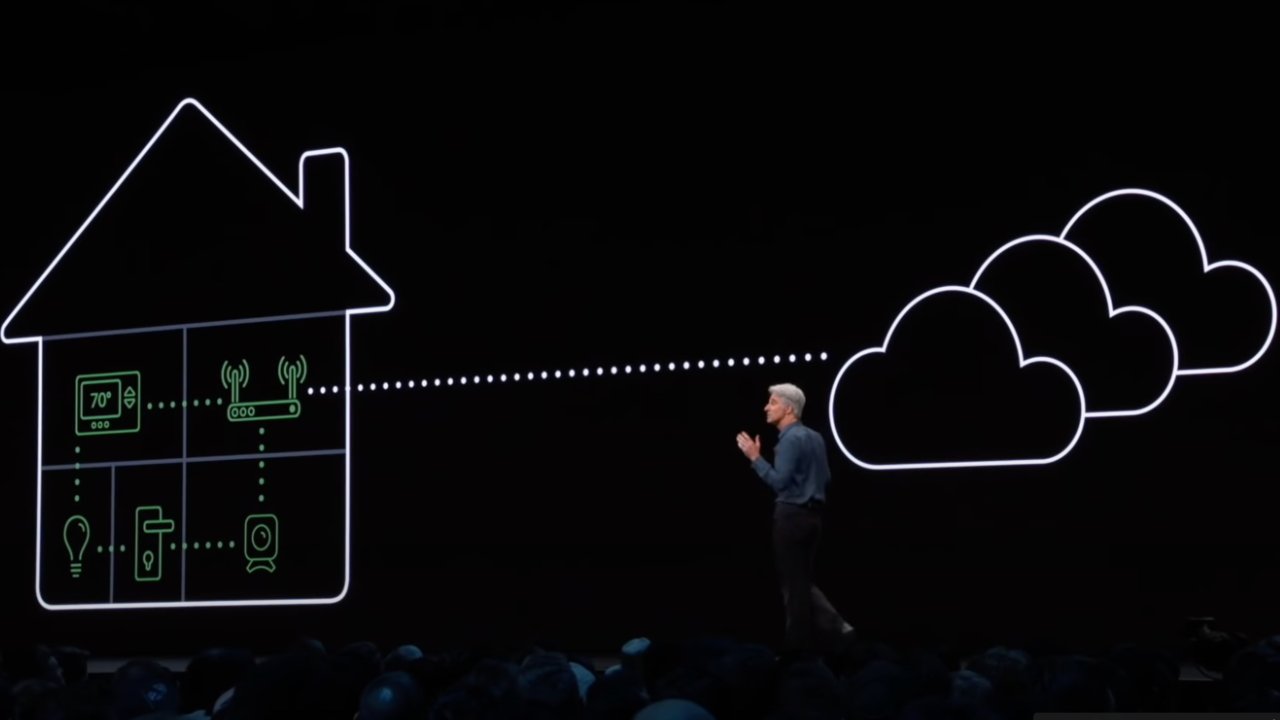 Craig Federighi gestures towards a large graphic showing a simplified, outlined house connected by dotted lines to stylized clouds, representing secure router technology