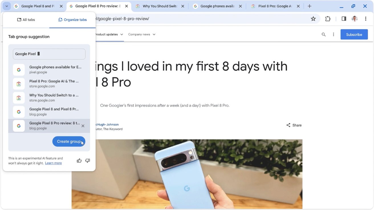 A hand holding a blue smartphone with the Google logo, in front of an open laptop displaying a blog post about the phone.
