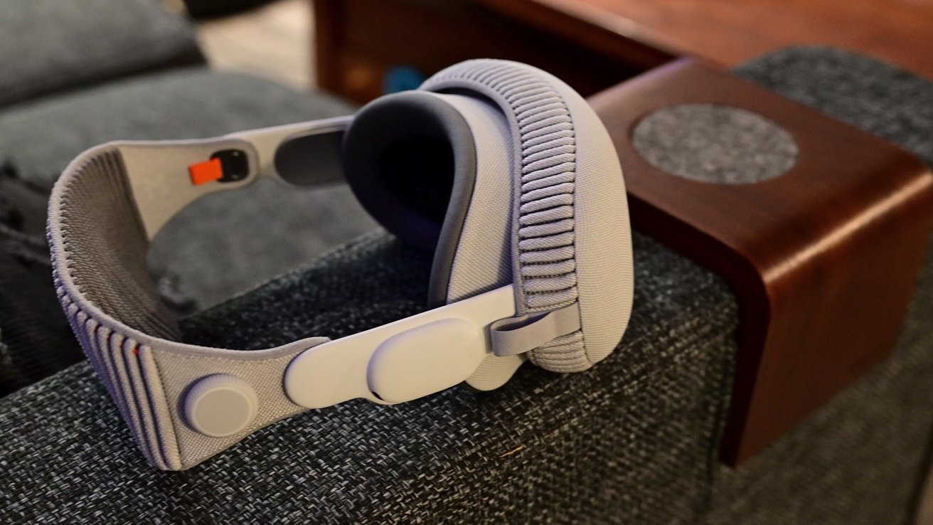 Close-up of Apple Vision Pro resting on textured fabric sofa arm, with a wooden armrest in the background.
