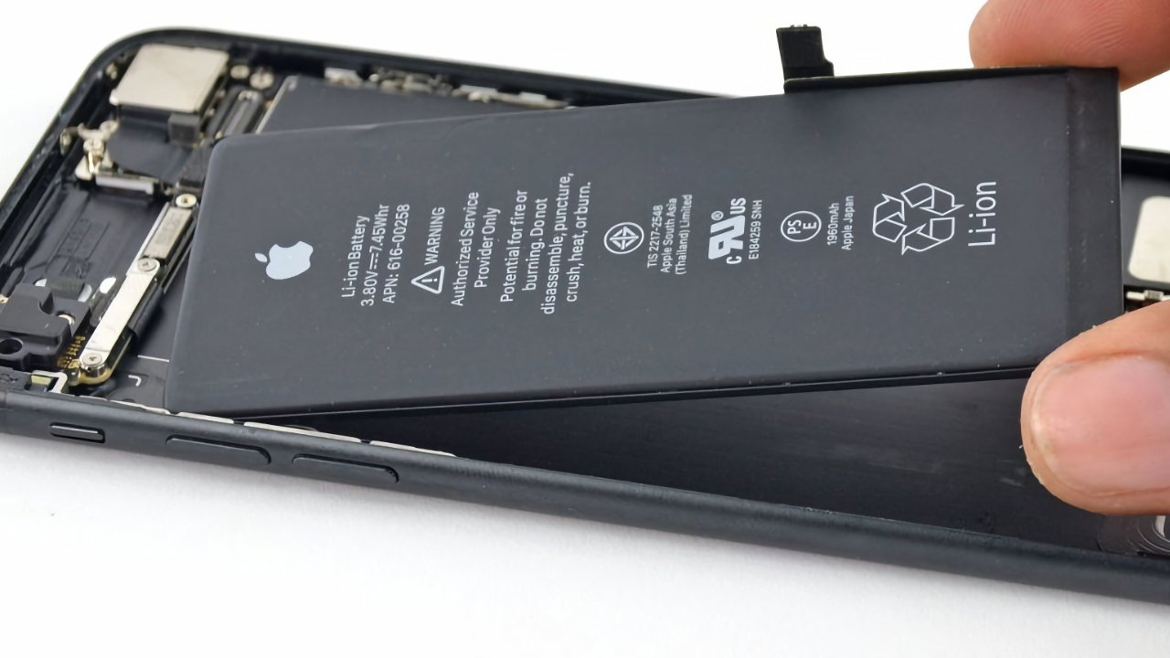 Opened smartphone showing its internal battery and components, with a hand holding one side.