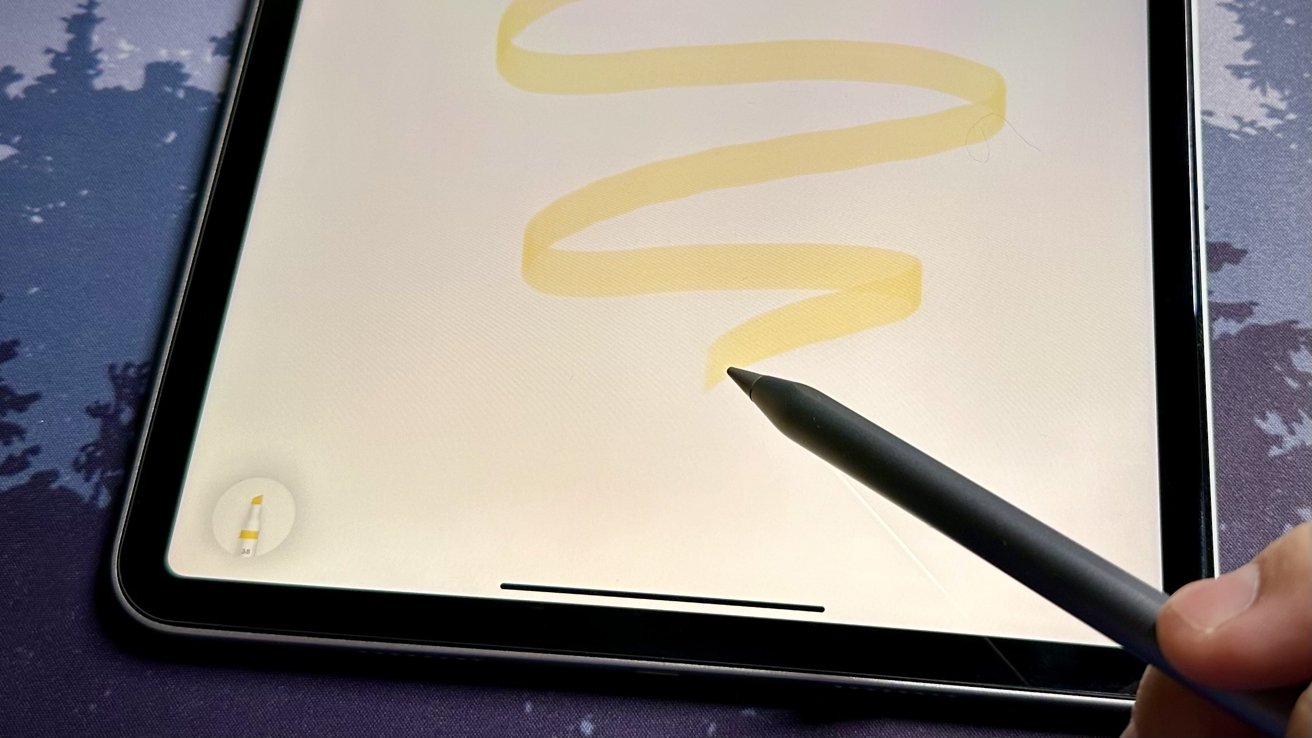 A close-up of a hand holding a stylus drawing a yellow squiggle on a digital tablet screen.