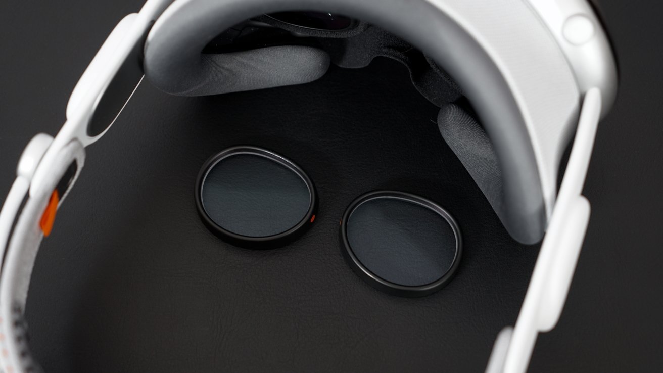 Optical inserts laying on a black leather mat in the center of the Apple Vision Pro, which is facing the top right of the photo in a top-down view.