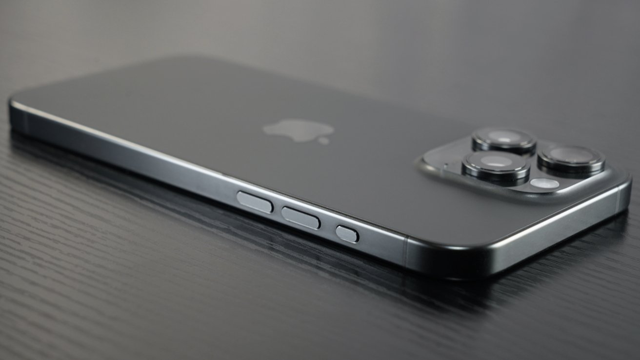 The space black iPhone 15 Pro Max lays facedown on a black surface