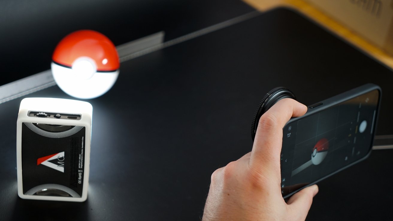 A bright light shines on a Pokeball while an iPhone with an ND filter takes a photo
