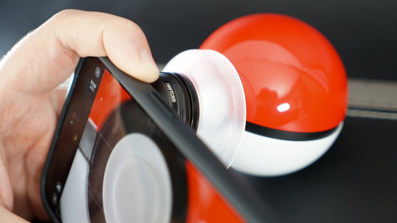 An iPhone with a macro lens attached set on top of a Pokeball for a close up shot