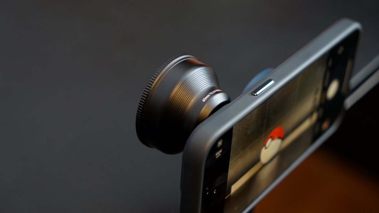 An iPhone on a tripod with a large lens attached. A Pokeball is visible in the viewfinder.