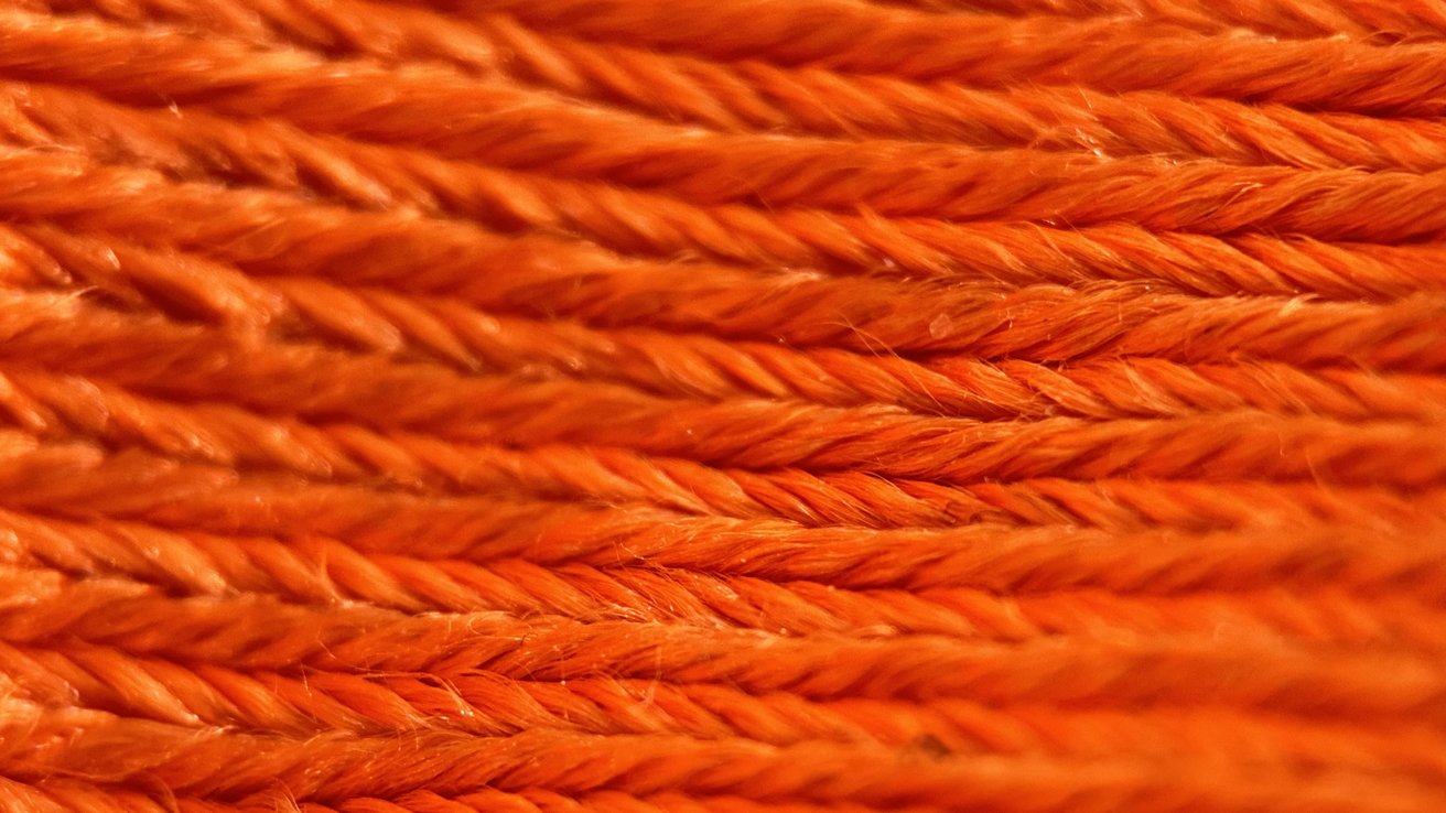 A close up shot of an orange cleaning cloth shows intricate details of the cloths' fabric