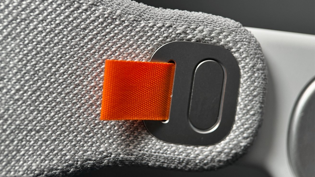 A close up shot of the Solo Knit Band attached to the Apple Vision Pro, showing the orange pull tab that disconnects it