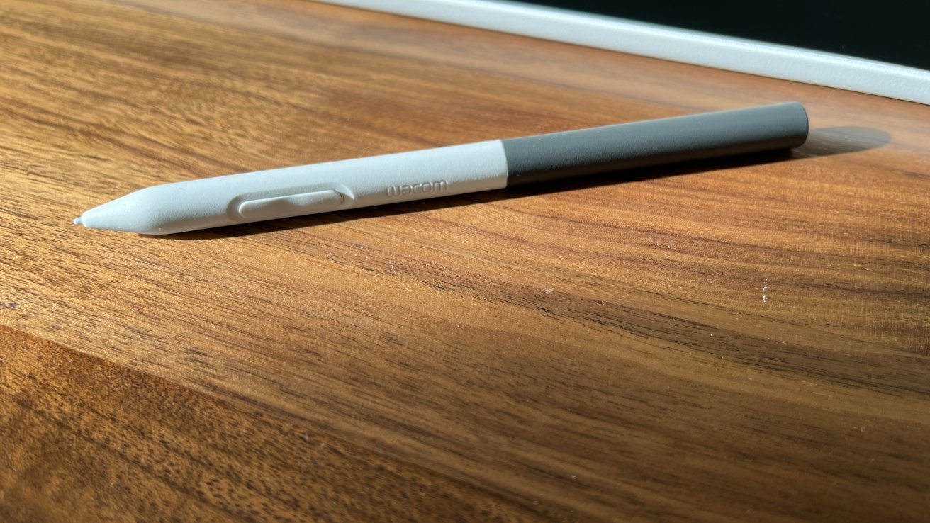 A Wacom stylus resting on a wooden table with warm lighting.