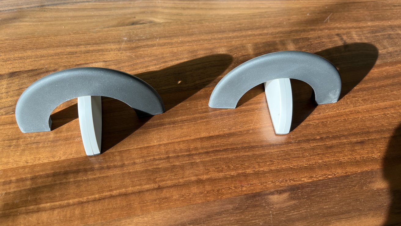 Two semi-circular gray objects with white bases on a wooden surface, creating a symmetrical appearance.