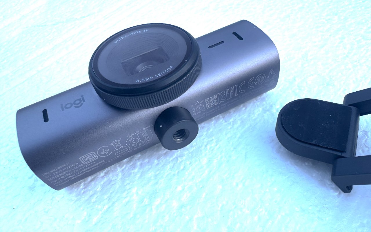 A Logitech webcam with a large lens and a detachable clip, resting on a textured surface.