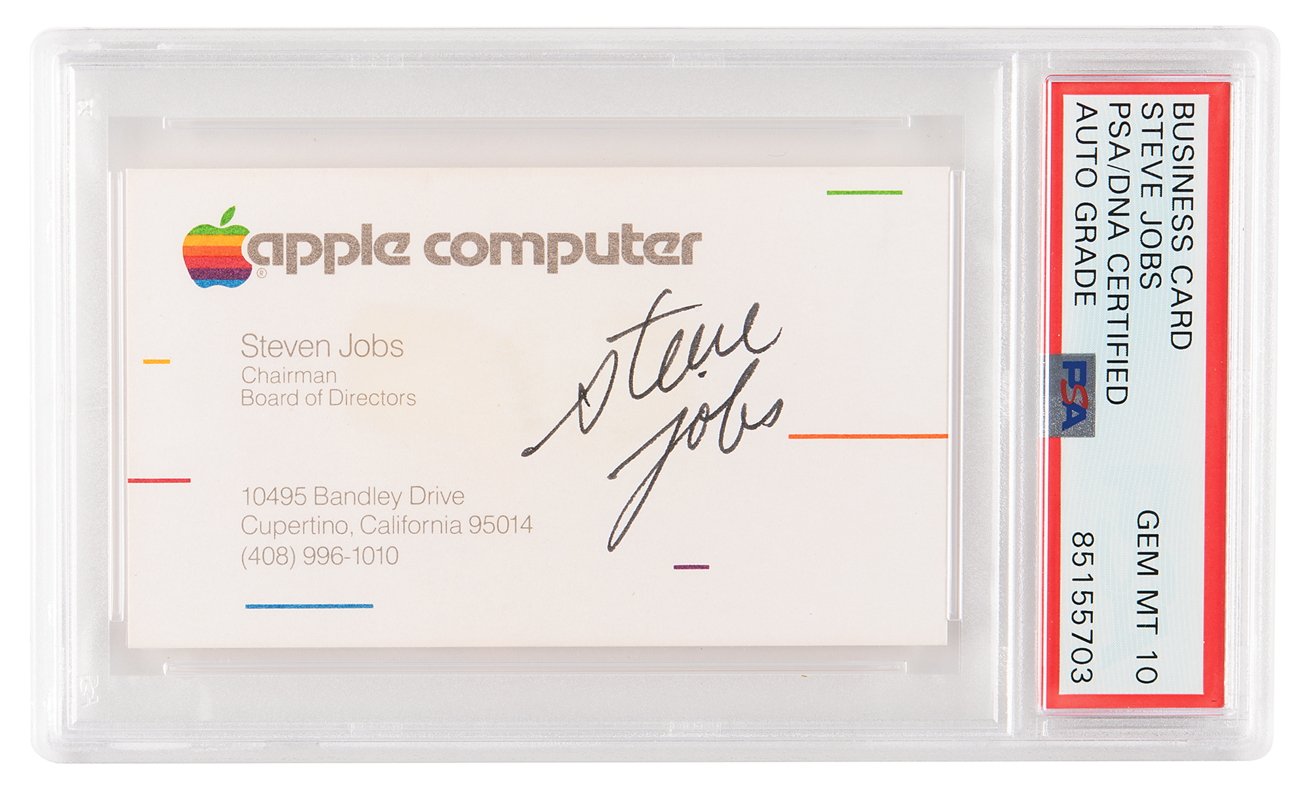 Steve Jobs's business card from Apple Computer, showing his name, title, and contact information, encased in a protective graded holder.
