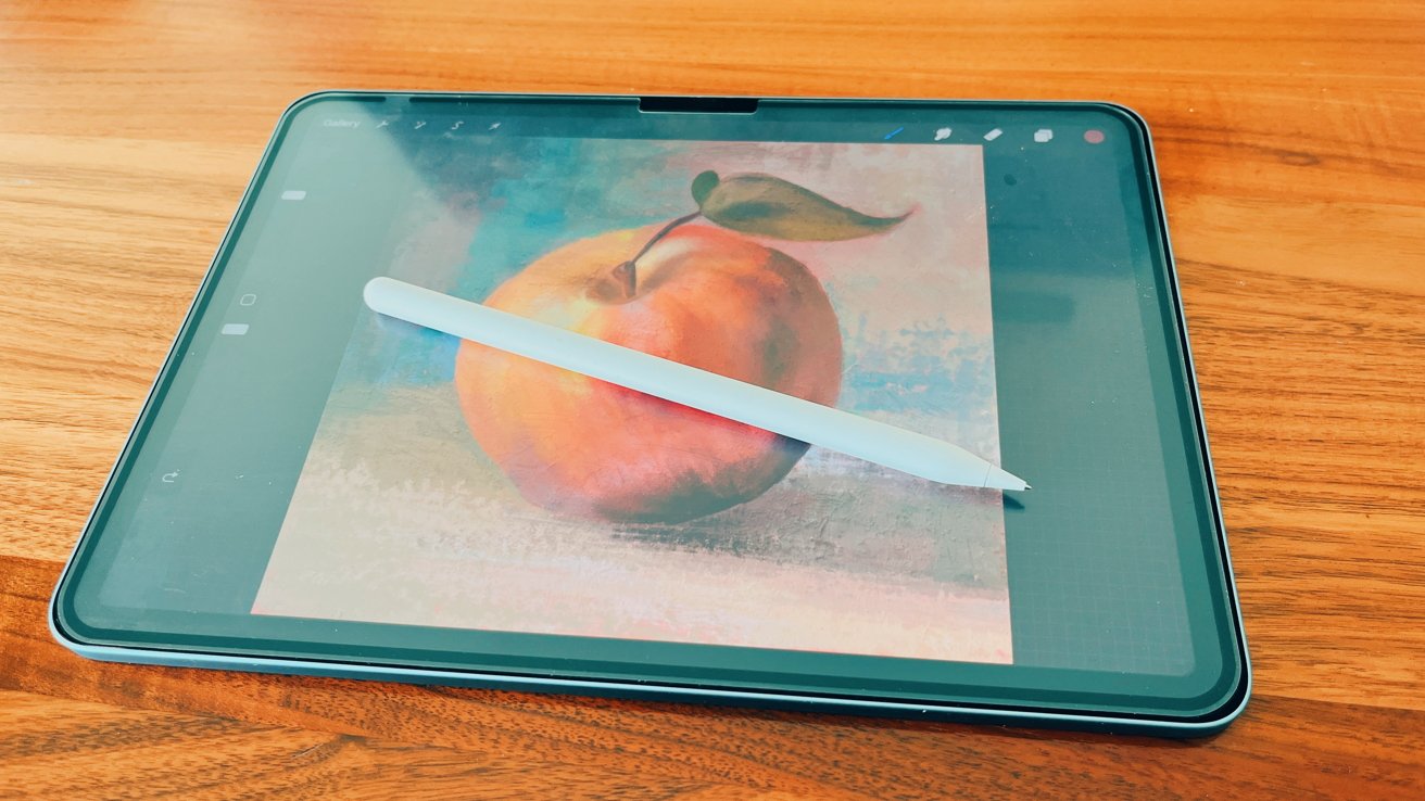 An iPad lying on a wooden surface displaying a painting of an Apple with a stylus pen resting on its screen.