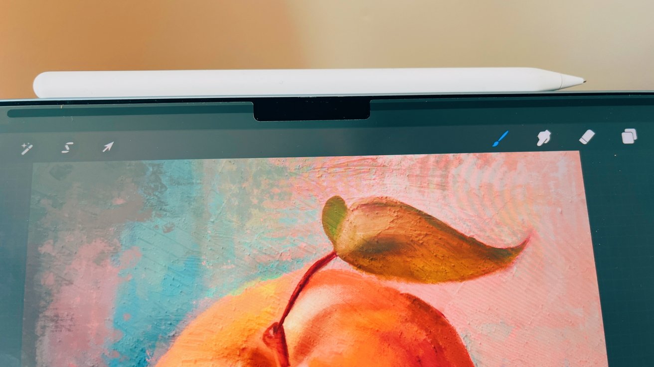 A stylus resting on a tablet displaying a digital painting of an apple with a textured background.