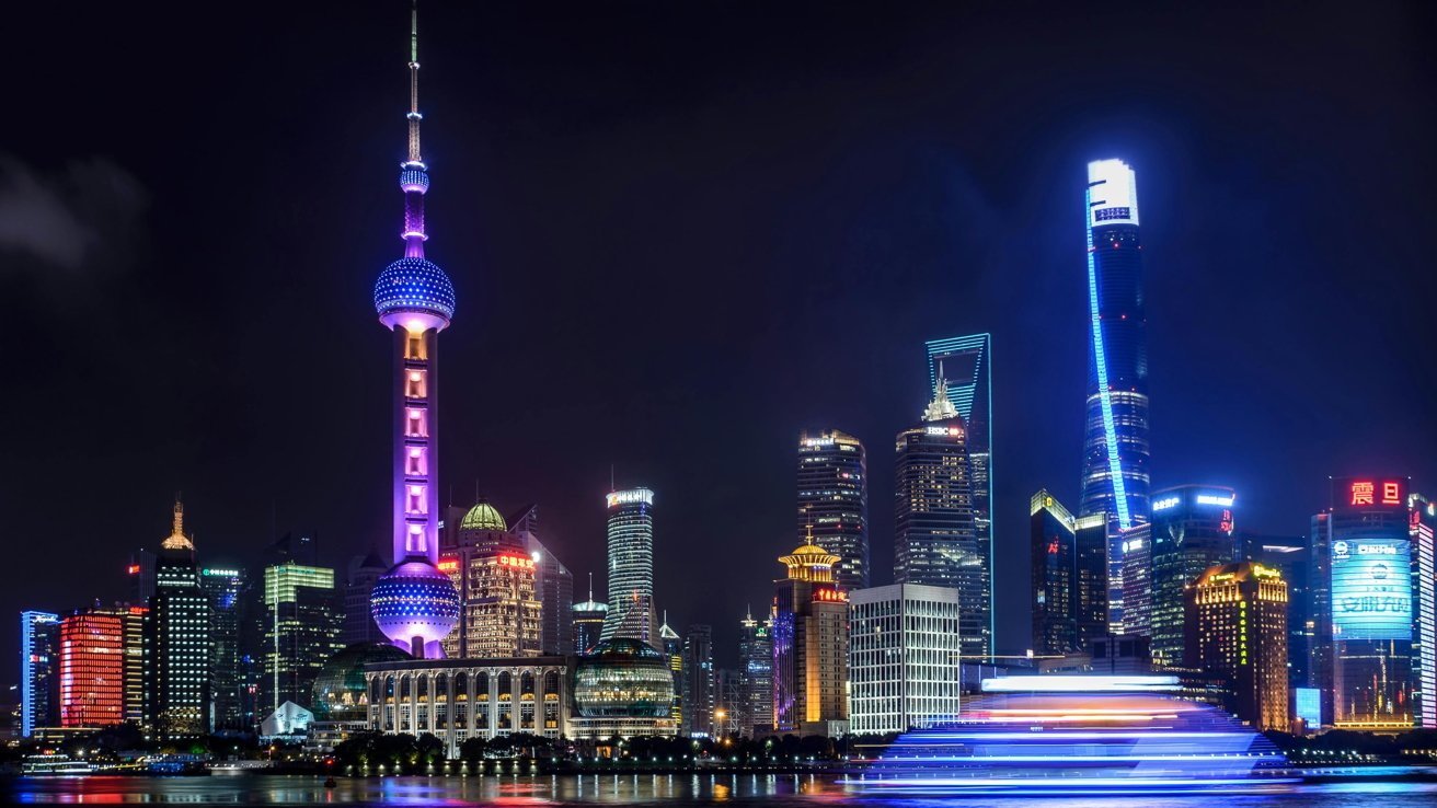 Shanghai skyline at night with illuminated Oriental Pearl Tower and modern skyscrapers reflecting in the water.