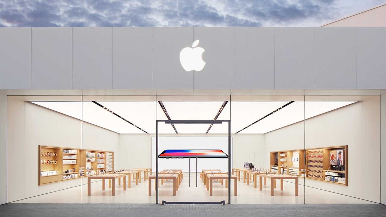 Exterior view of an Apple Store with a minimalist design, featuring a large glass facade and the Apple logo above the entrance.