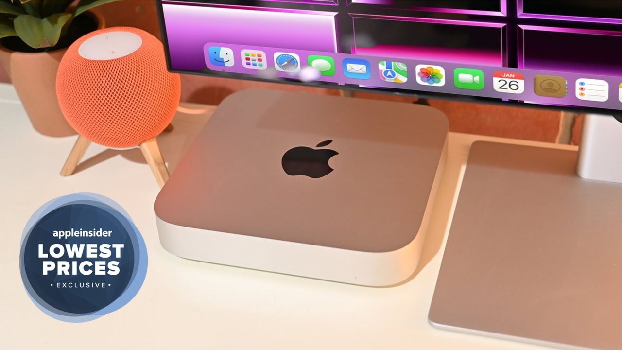Stolní sestava s Macem mini, oranžovým inteligentním reproduktorem HomePod mini, notebookem a monitorem s barevnou grafikou, označená jako exkluzivní nabídka.