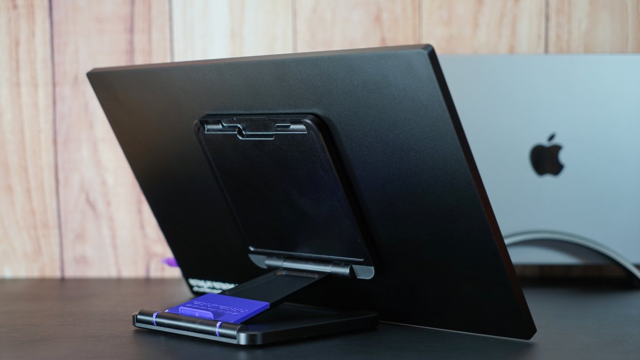A portable monitor with a magnetic stand folded low in a drawing position. A MacBook is visible in the background.