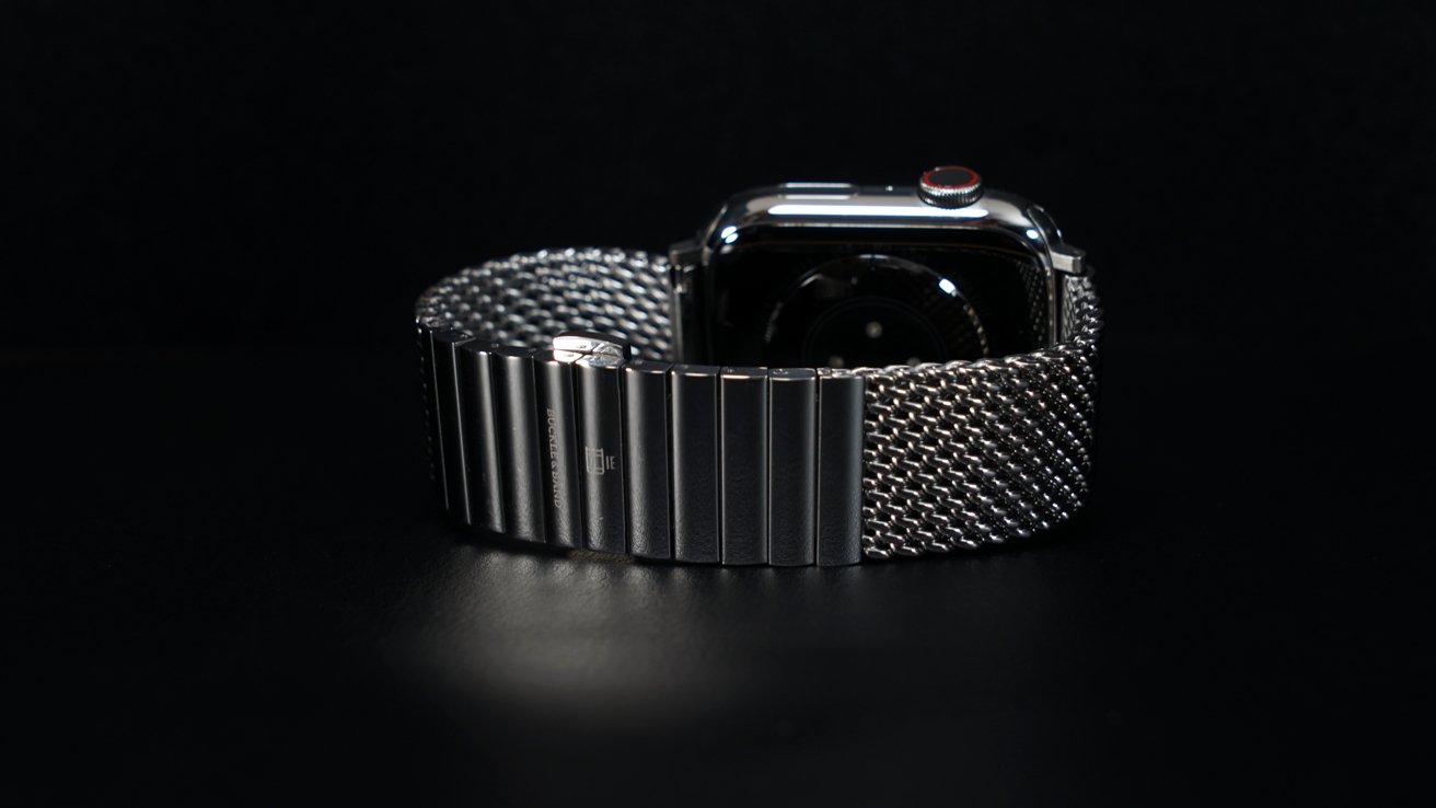 A stainless steel Apple Watch with a mesh link bracelet sitting elegantly on a dark table.
