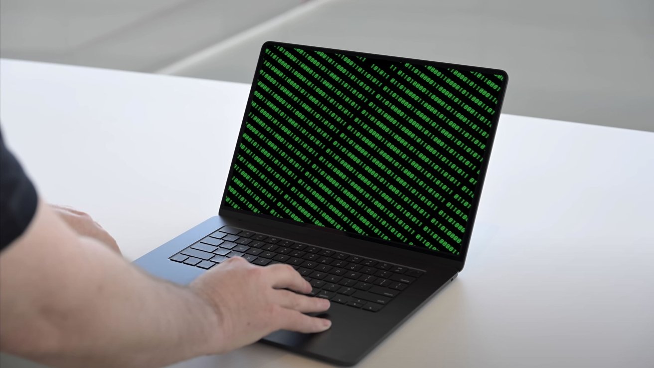 A person's hands typing on a laptop with green matrix-style code on the screen, placed on a white surface.