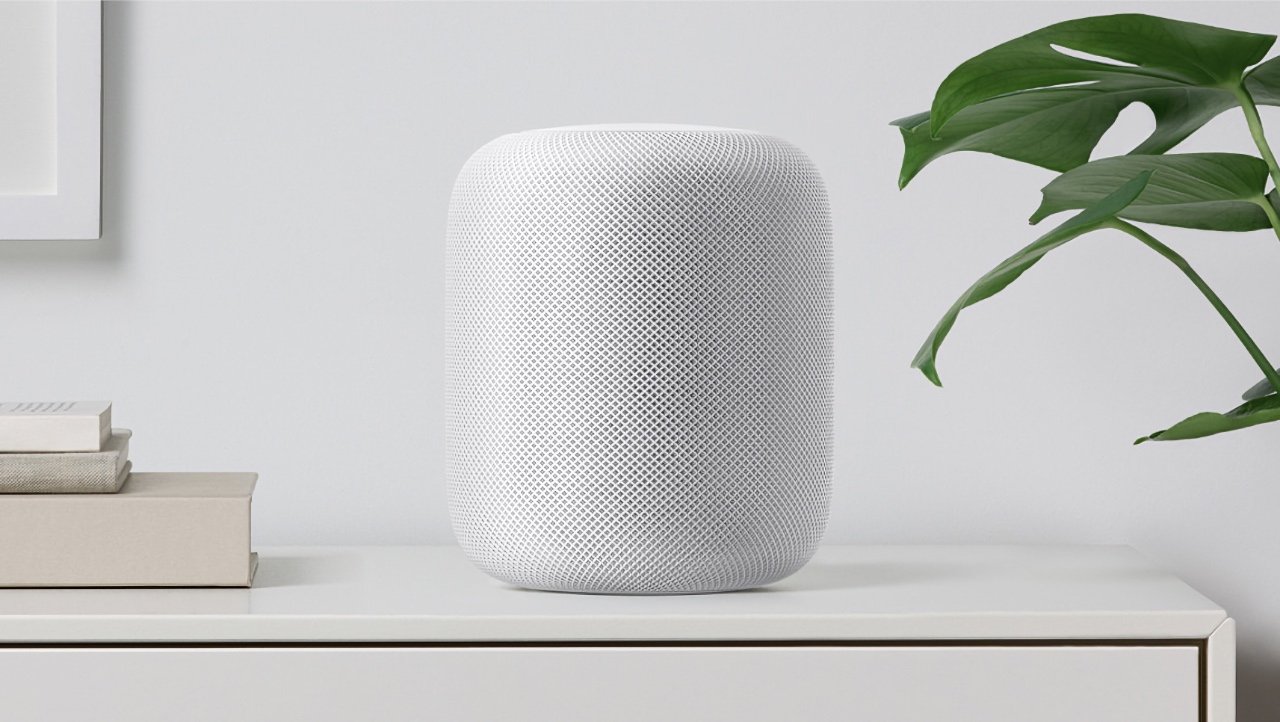White cylindrical HomePod speaker on a shelf with a plant and books in a minimalist room.