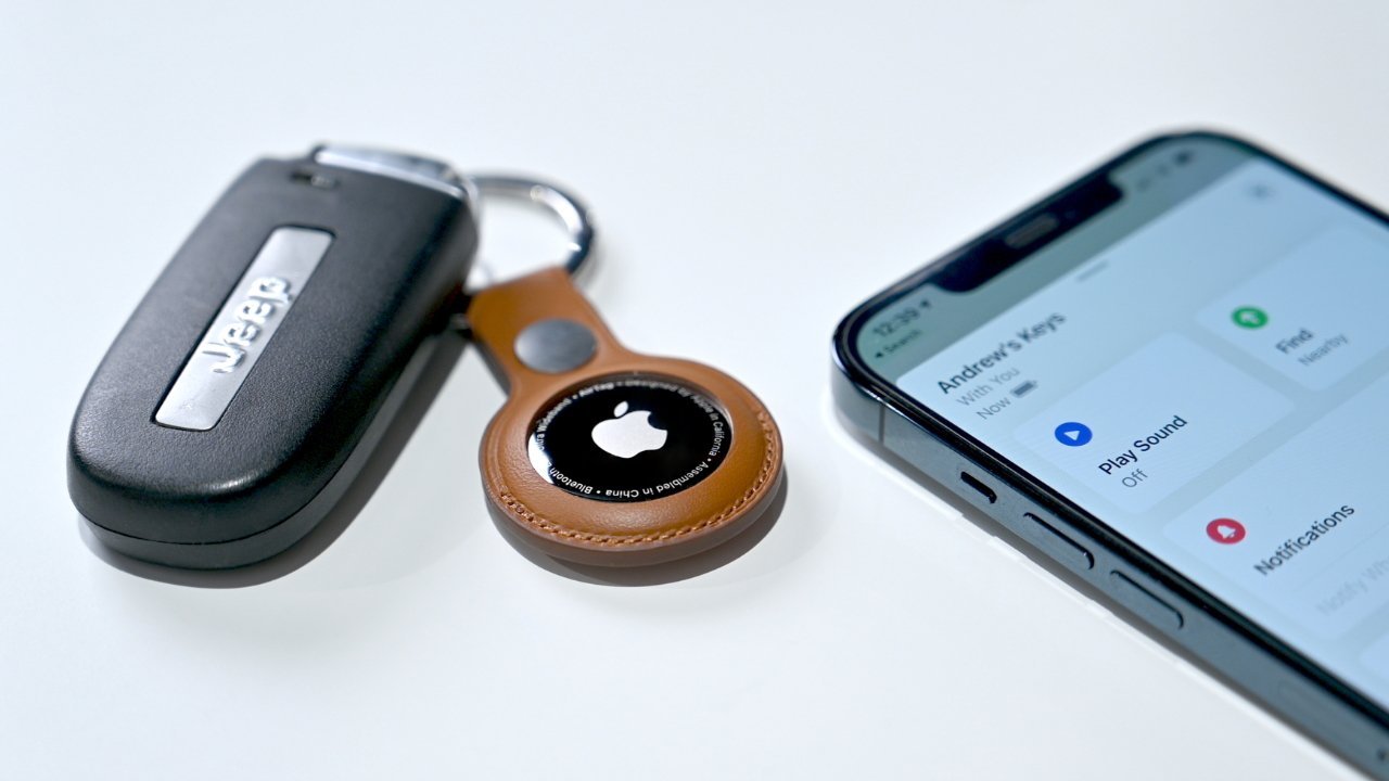 Car key, Apple AirTag in leather holder, and iPhone displaying location app on white background.