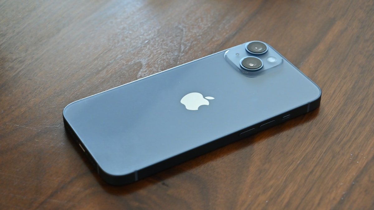 A blue iPhone with a dual-camera system on a wooden surface.