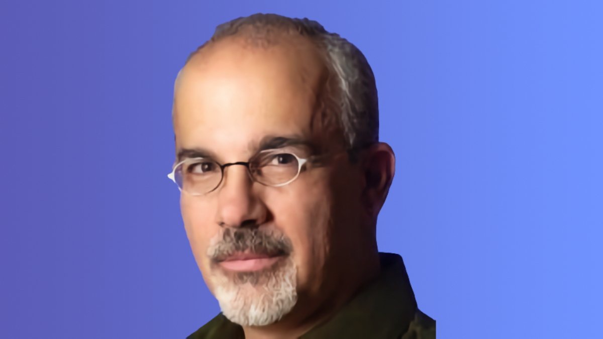 Frank Casanova with glasses and goatee against a blue background.