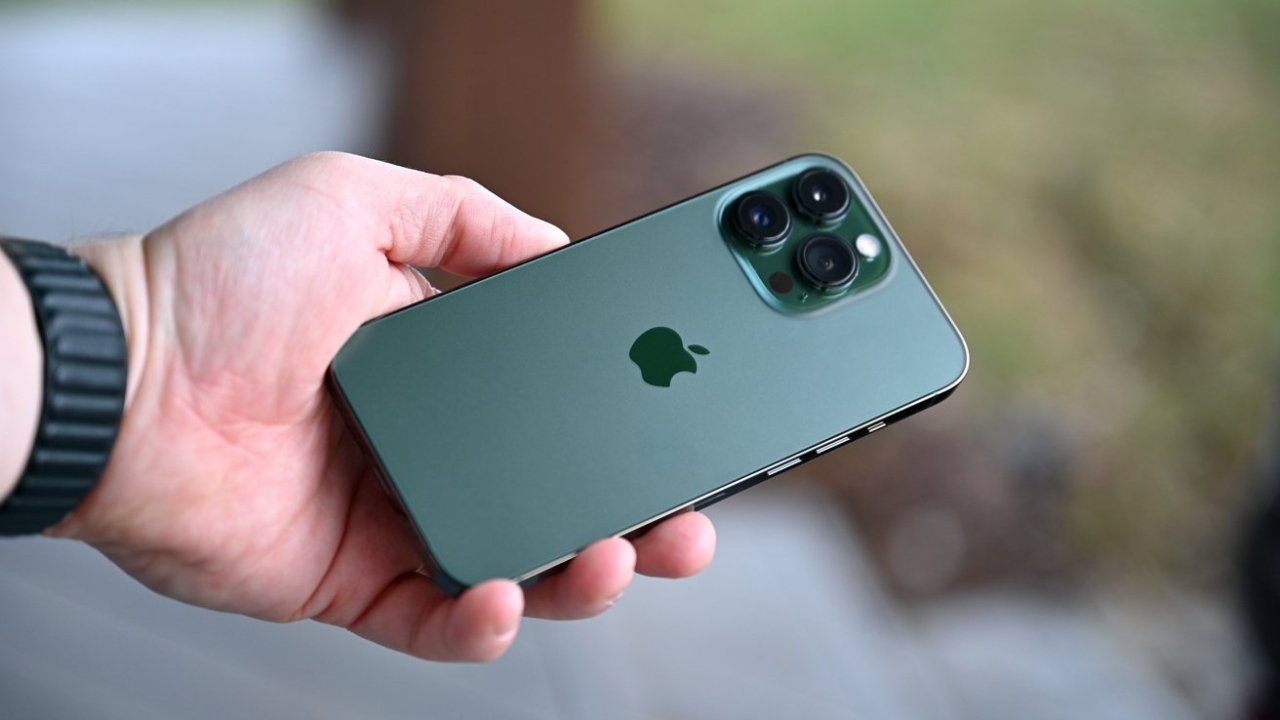 Hand holding a green smartphone with a triple camera setup.