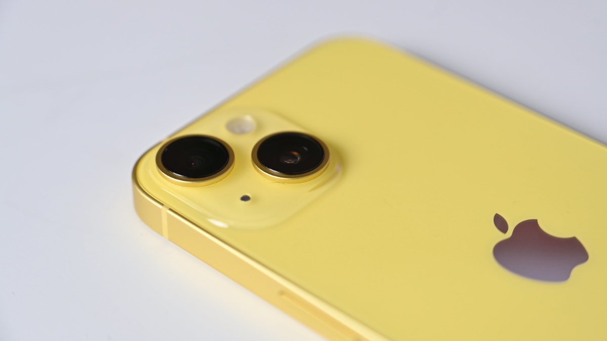 Close-up of an iPhone 14's dual camera lenses, flash, and logo on a white background.