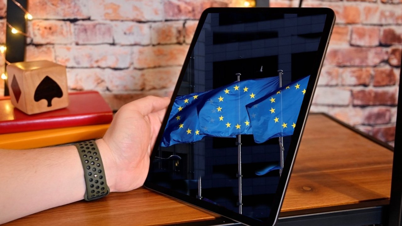 A person's arm holding a tablet that displays a European Union flag, suggesting augmented reality, with warm interior background.