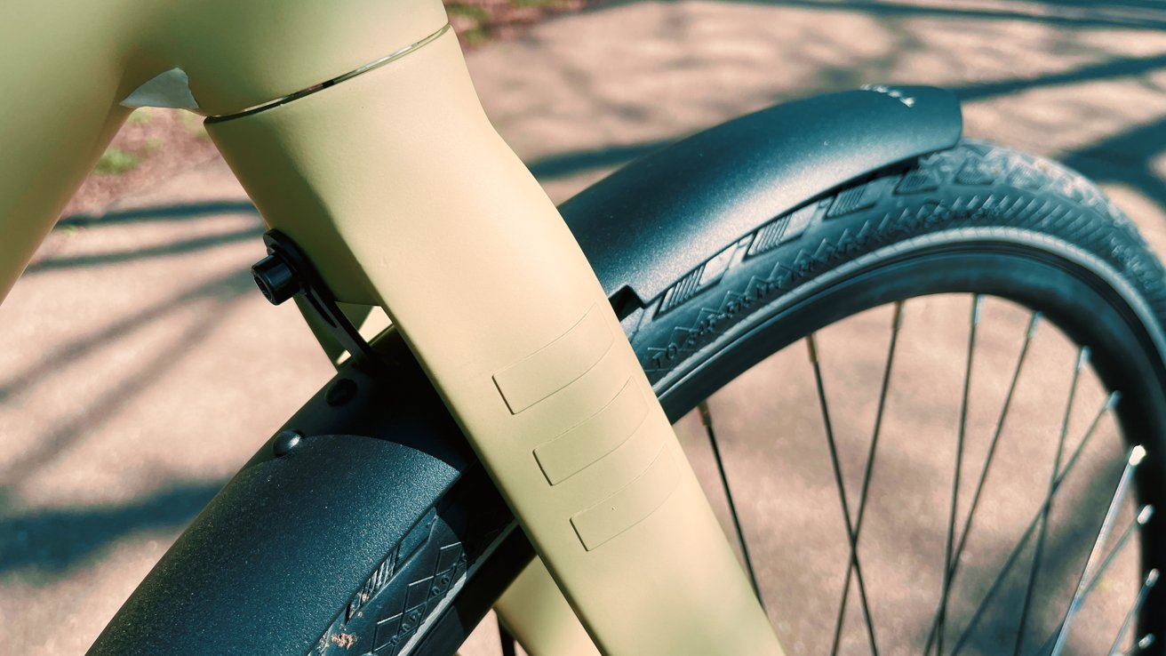 Close-up of a bicycle frame with a focus on the front wheel and fender in bright sunlight.
