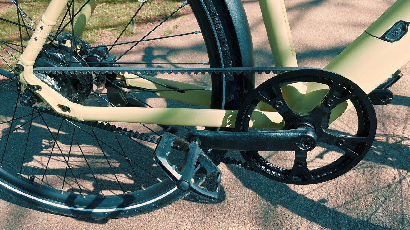 Close-up of a bicycle's belt and gears with focus on the crankset and rear wheel components.