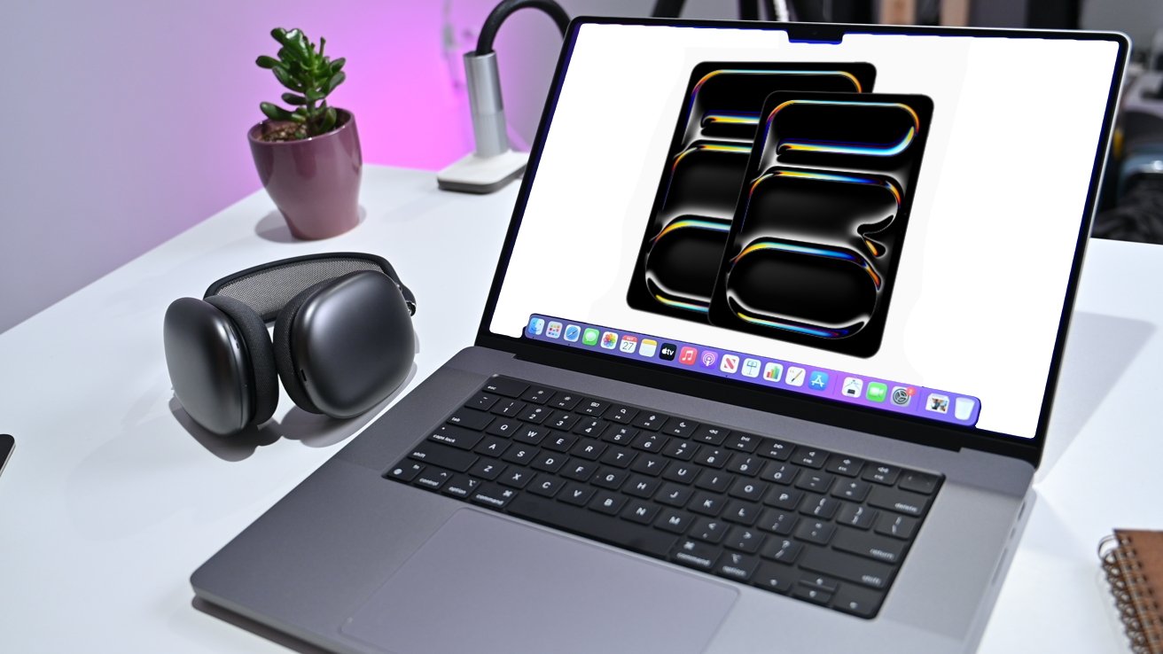 Laptop with colorful abstract wallpaper on screen, over-ear headphones, and a potted plant on a white desk with pink lighting in the background.