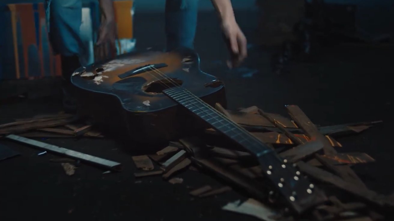 A person picks up a broken guitar