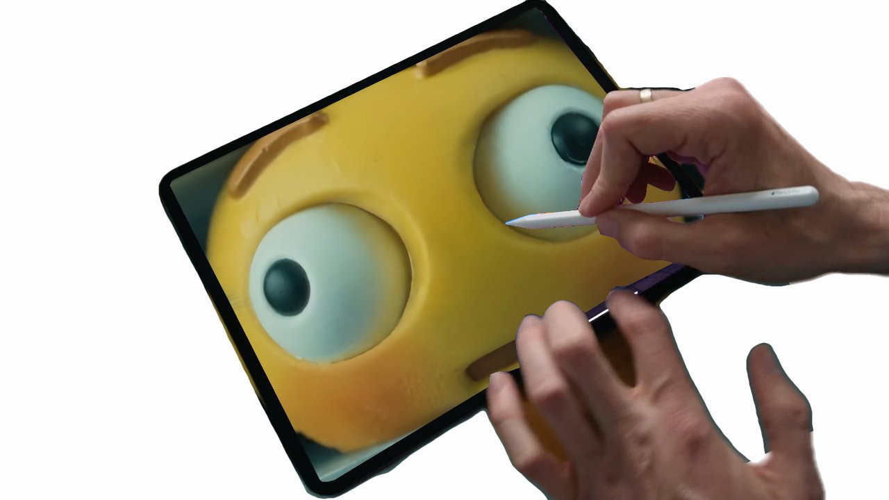 Hand drawing on a tablet screen displaying a close-up of a stress ball's face with a stylus pen.