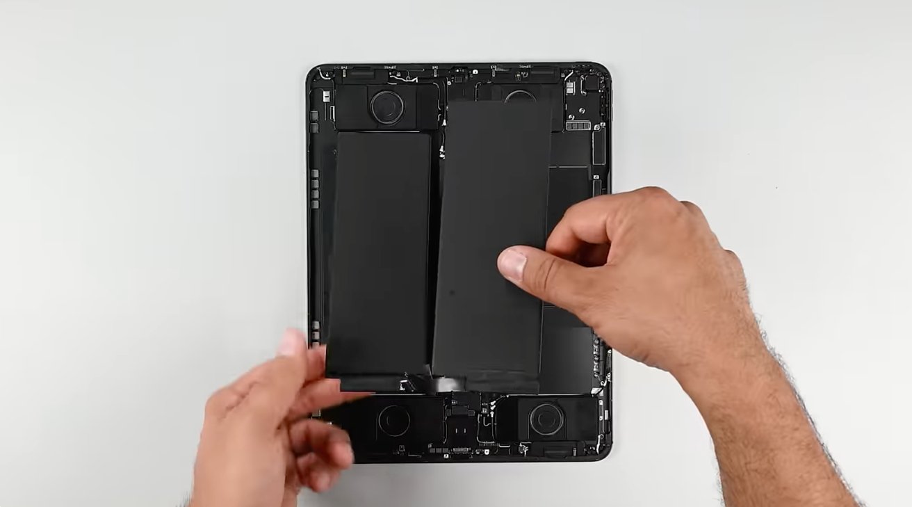 Man lifting one of the two battery packs out of a disassembled 13-inch iPad Pro