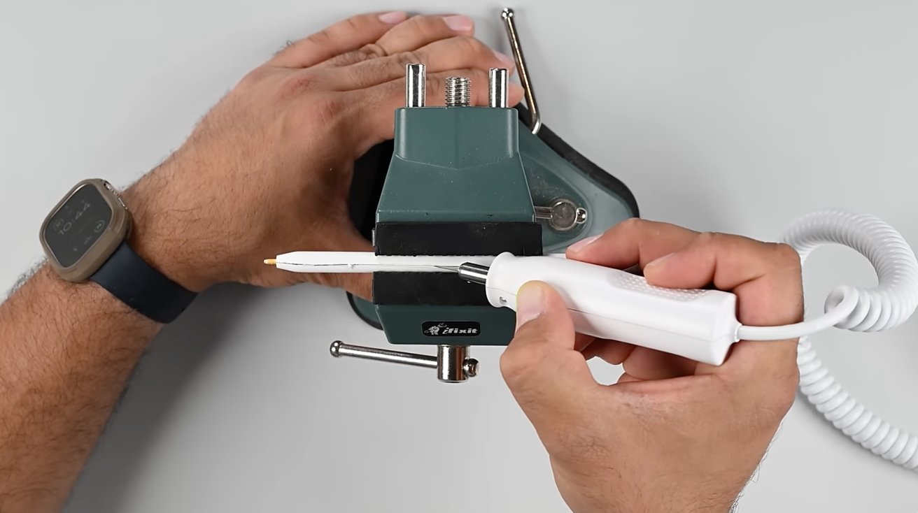 Man using a sonic cutter to slice open an Apple Pencil Pro's plastic housing.