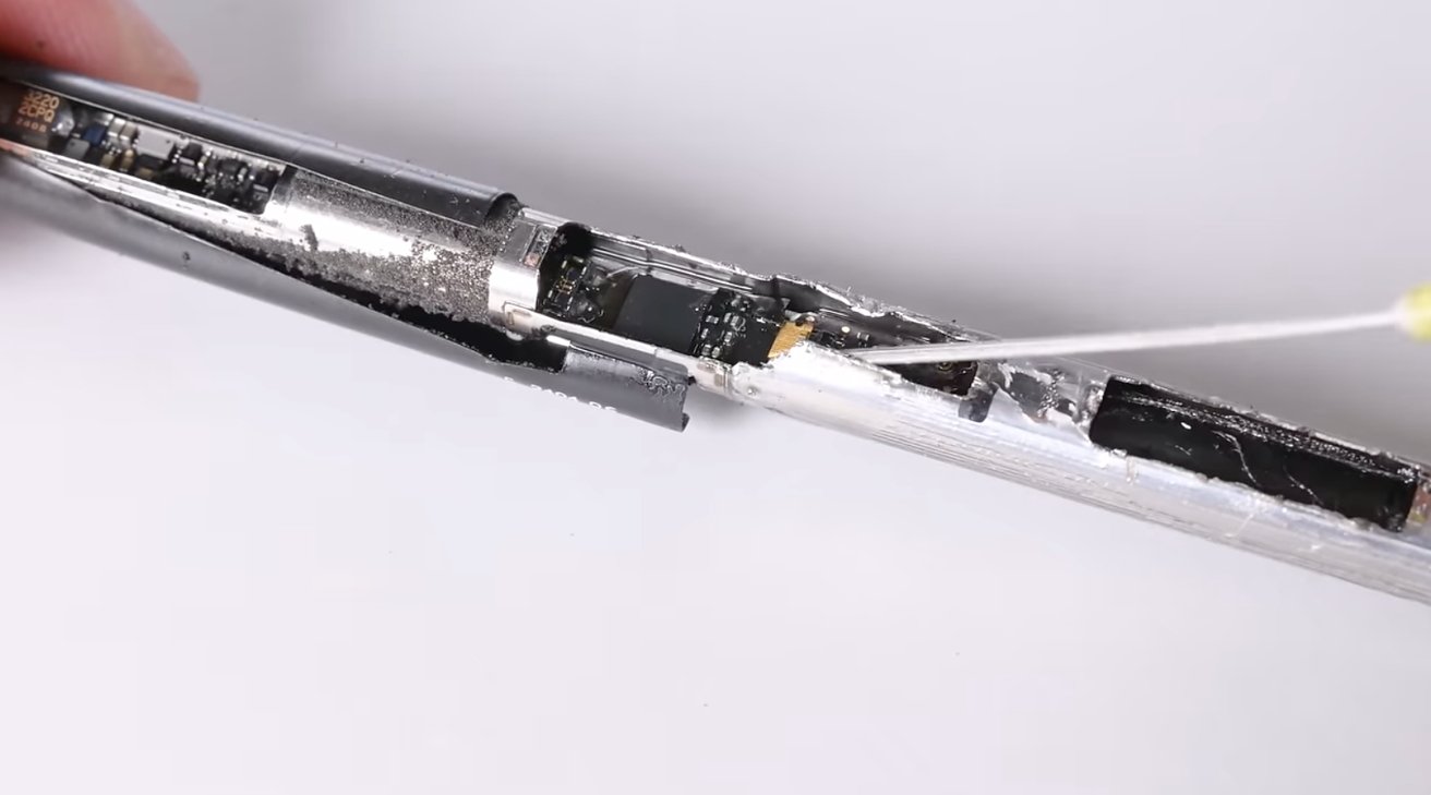 Man holding a disassembled Apple Pencil Pro part with tweezers