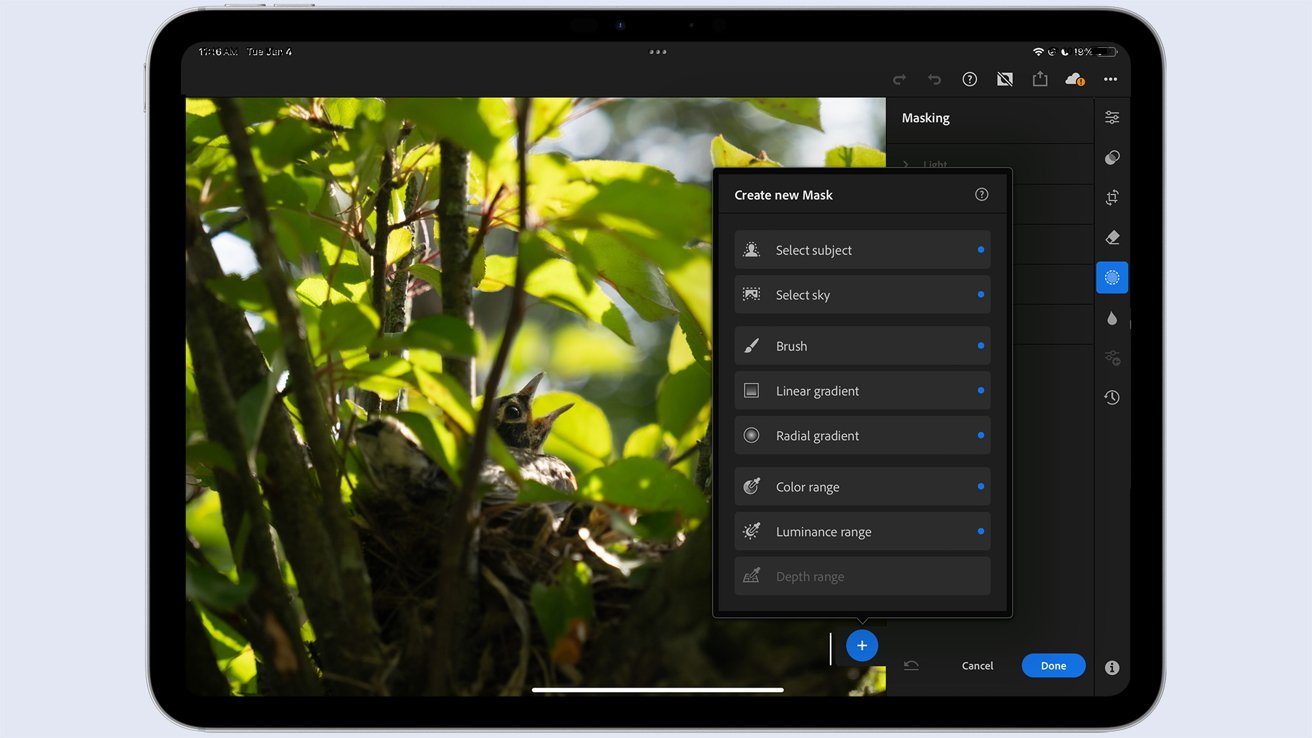 A tablet displaying photo editing software, with a bird in a nest among dense green foliage and a menu for creating new masks.Pad