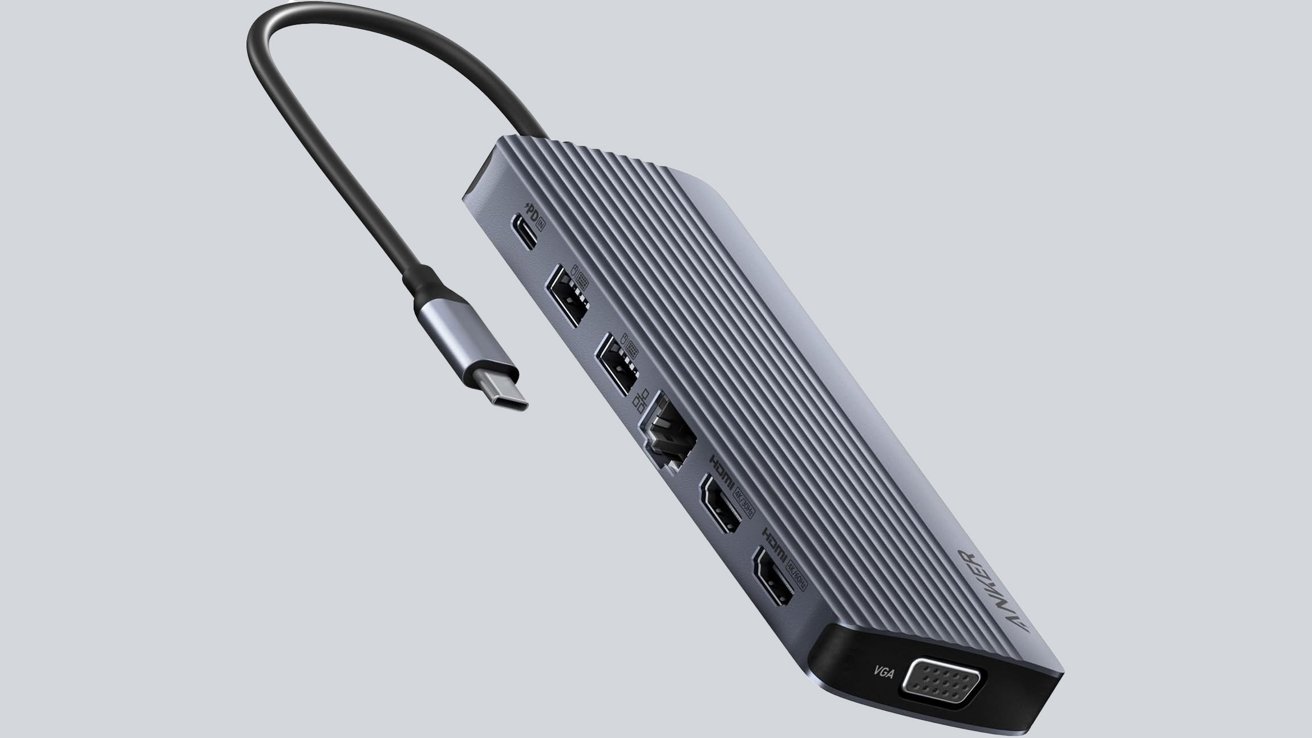 Rectangular USB-C hub with multiple ports, including USB, Ethernet, HDMI, VGA, and a power delivery port. Connected cable protruding from the top.