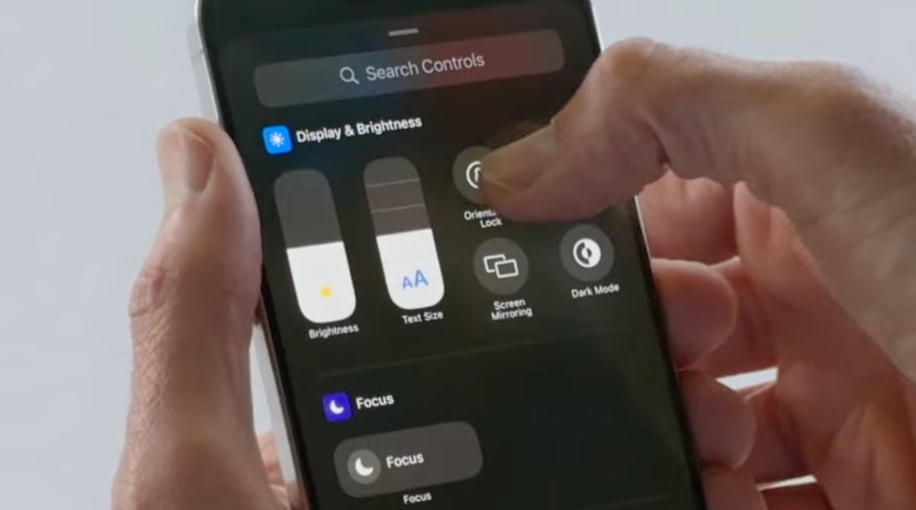 Hand adjusting settings on a smartphone screen, including brightness, text size, orientation lock, screen mirroring, dark mode, and focus.