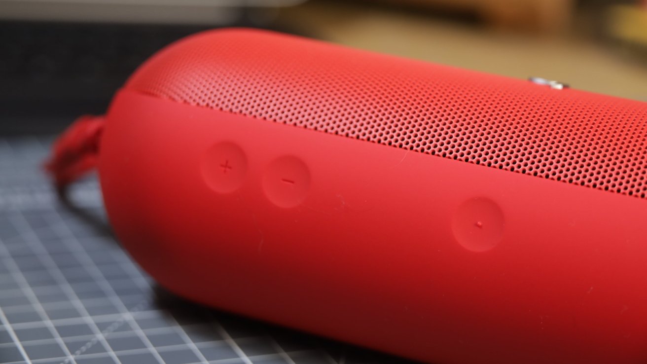 A red cylindrical Bluetooth speaker with volume control buttons and a textured pattern on the surface.